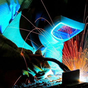 Participant practicing MIG welding with sparks under supervision